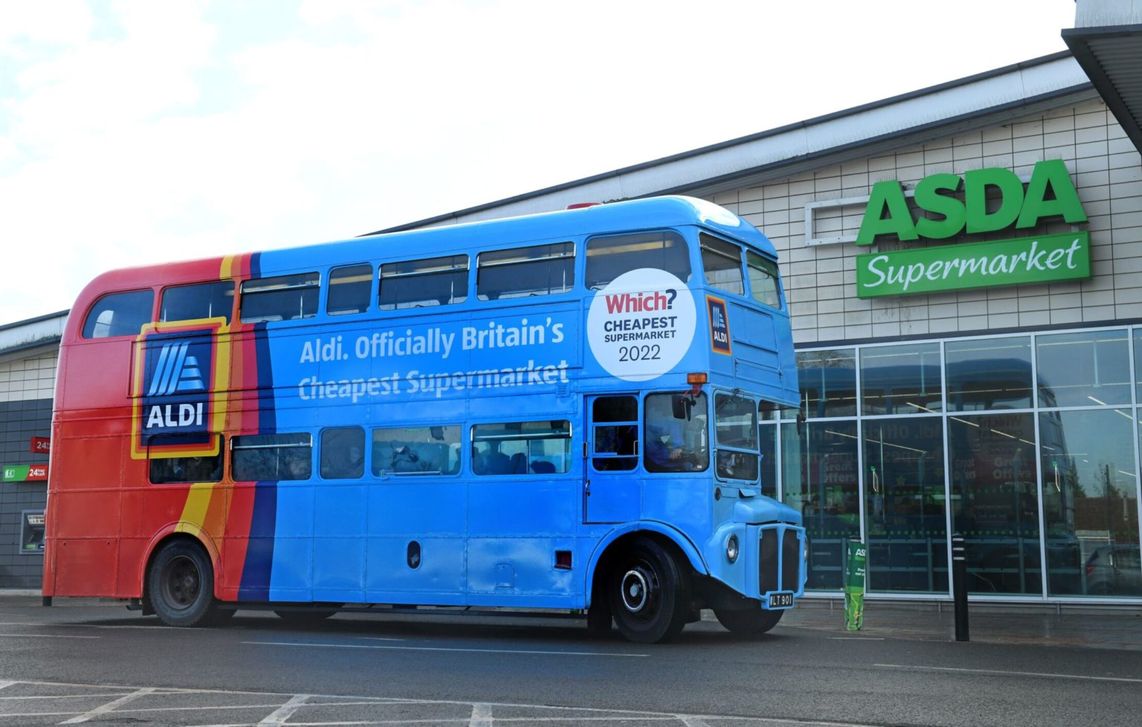 Aldi wrapped double-decker bus promoting 'Cheapest Supermarket 2022' parked outside an ASDA store.