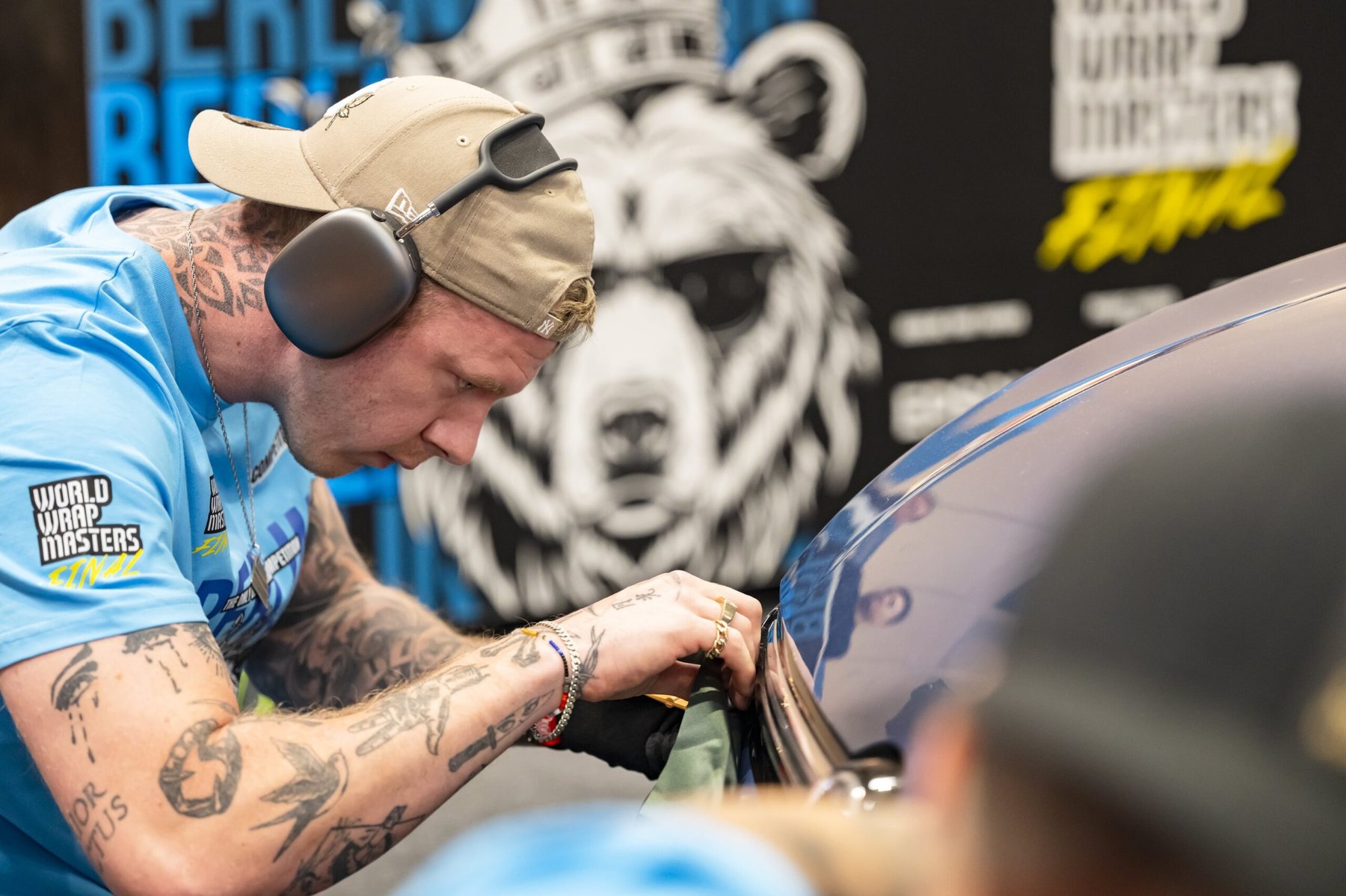 A competitor applies vinyl wrap to a vehicle panel during the World Wrap Masters Final competition.