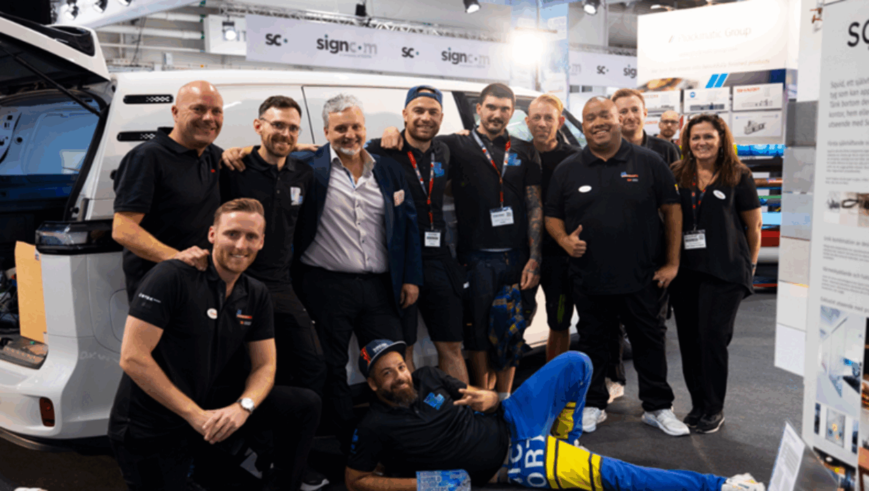 A group of smiling vehicle wrap professionals pose next to a white van at the FESPA Wrap Masters competition.