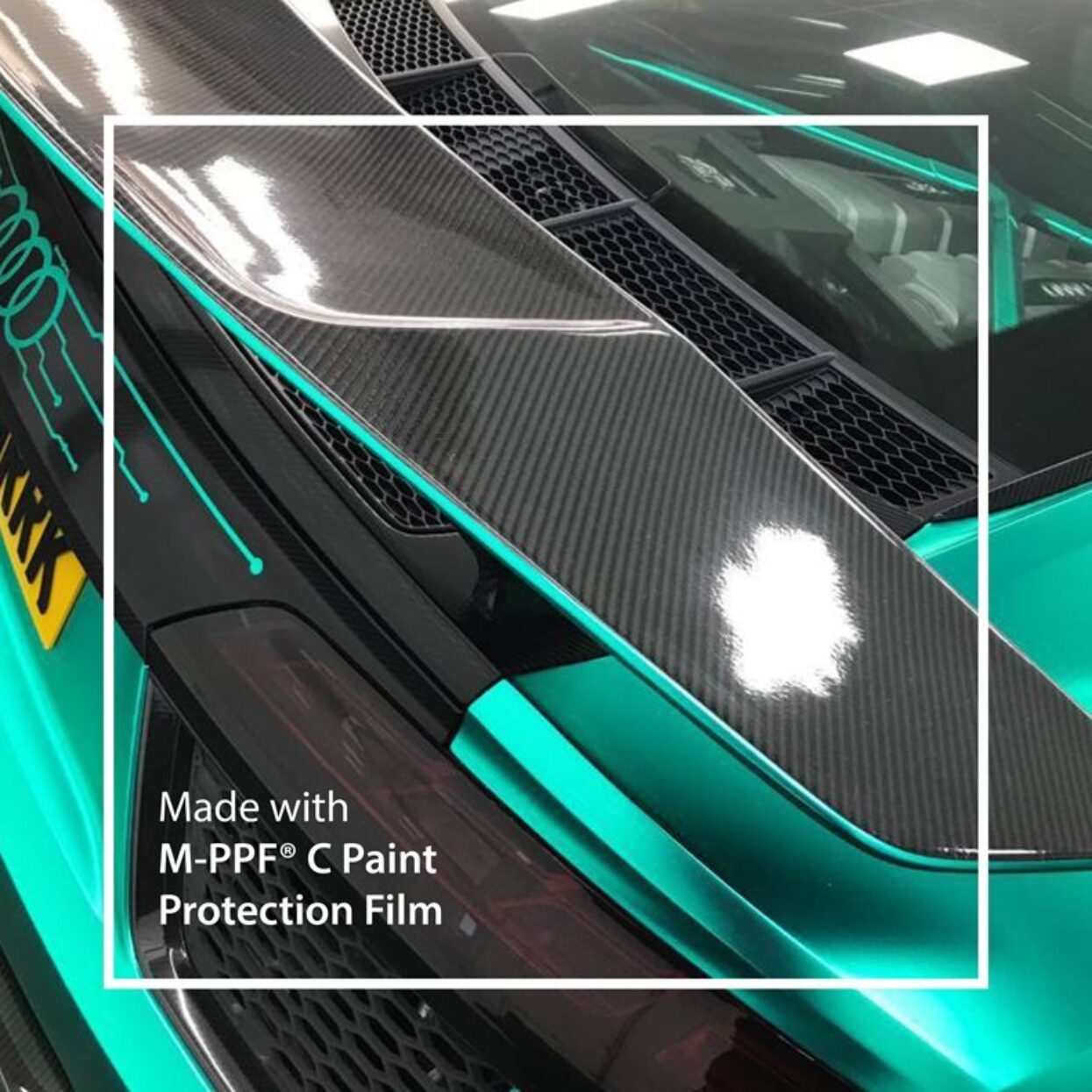Close-up of a wrapped car showing glossy carbon fibre and teal M-PPF C Paint Protection Film.