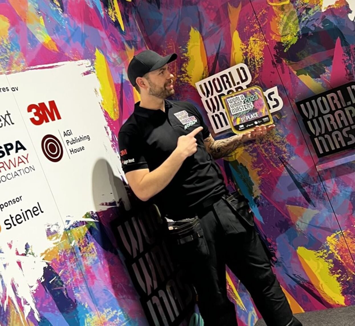 A man in a black cap holds the World Wrap Masters 2023 1st Place award.