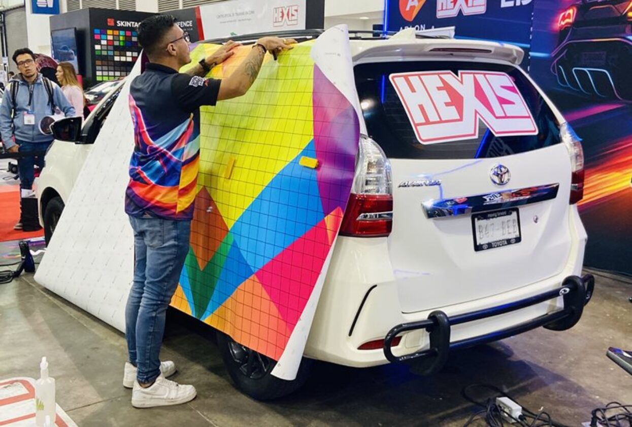 Vehicle wrapping competitor applying a bright, geometric vinyl graphic to a white van.
