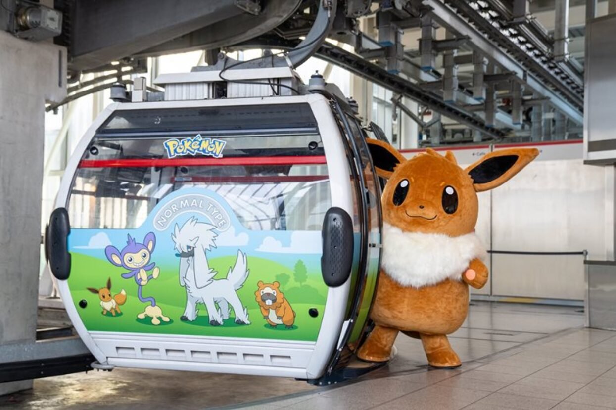 Pokemon wrapped cable car gondola with the Eevee mascot standing next to the door.